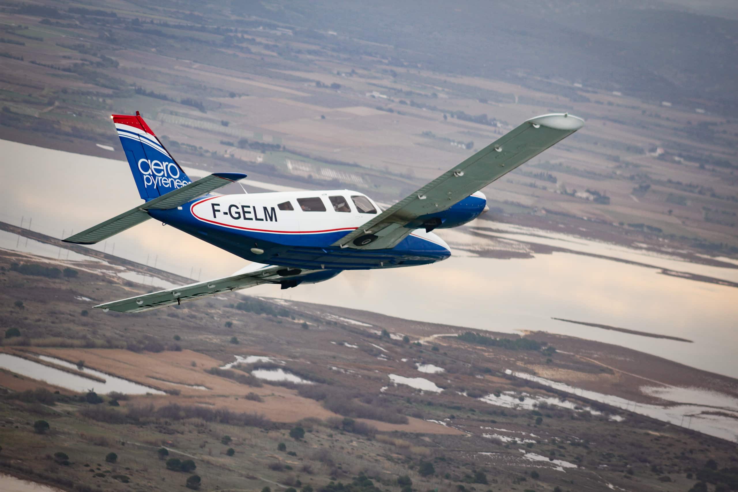 Avion bimoteur PA34 au couleur d'Aéropyrénées effectuant un virage en vol